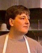 Young man with brown hair wearing a work apron